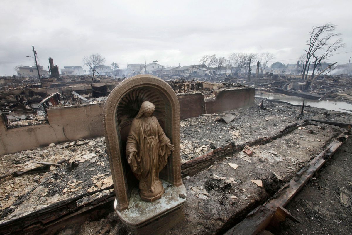 In this Oct. 30, 2012, file photo, a religious statue stands in the ashes of burned homes the morning after Superstorm Sandy raged through the community of Breezy Point in the Queens borough of New York. A fire that burned during the storm destroyed 130 neighboring houses in the oceanside community. The statue was preserved by the owner. (AP Photo/Mark Lennihan, File)  (AP)