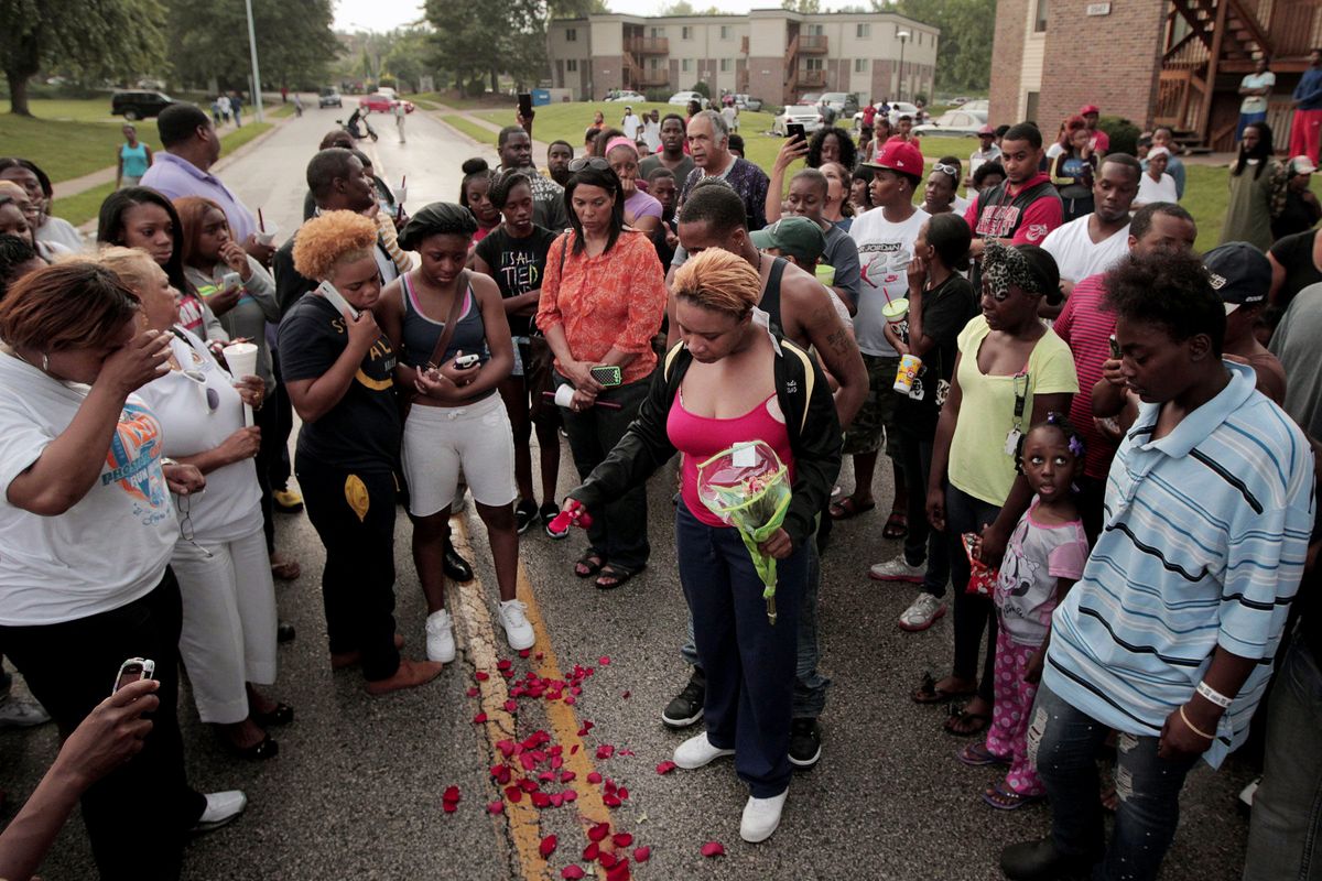 FILE- In this Aug. 9, 2014, file photo, Lesley McSpadden, center, drops rose petals on the blood stains from her 18-year-old son Michael Brown who was shot and killed a police officer in Ferguson, Mo. After Brown's death at the hands of a white police officer his legacy continues to evolve. (AP Photo/St. Louis Post-Dispatch, Huy Mach, File) (AP)