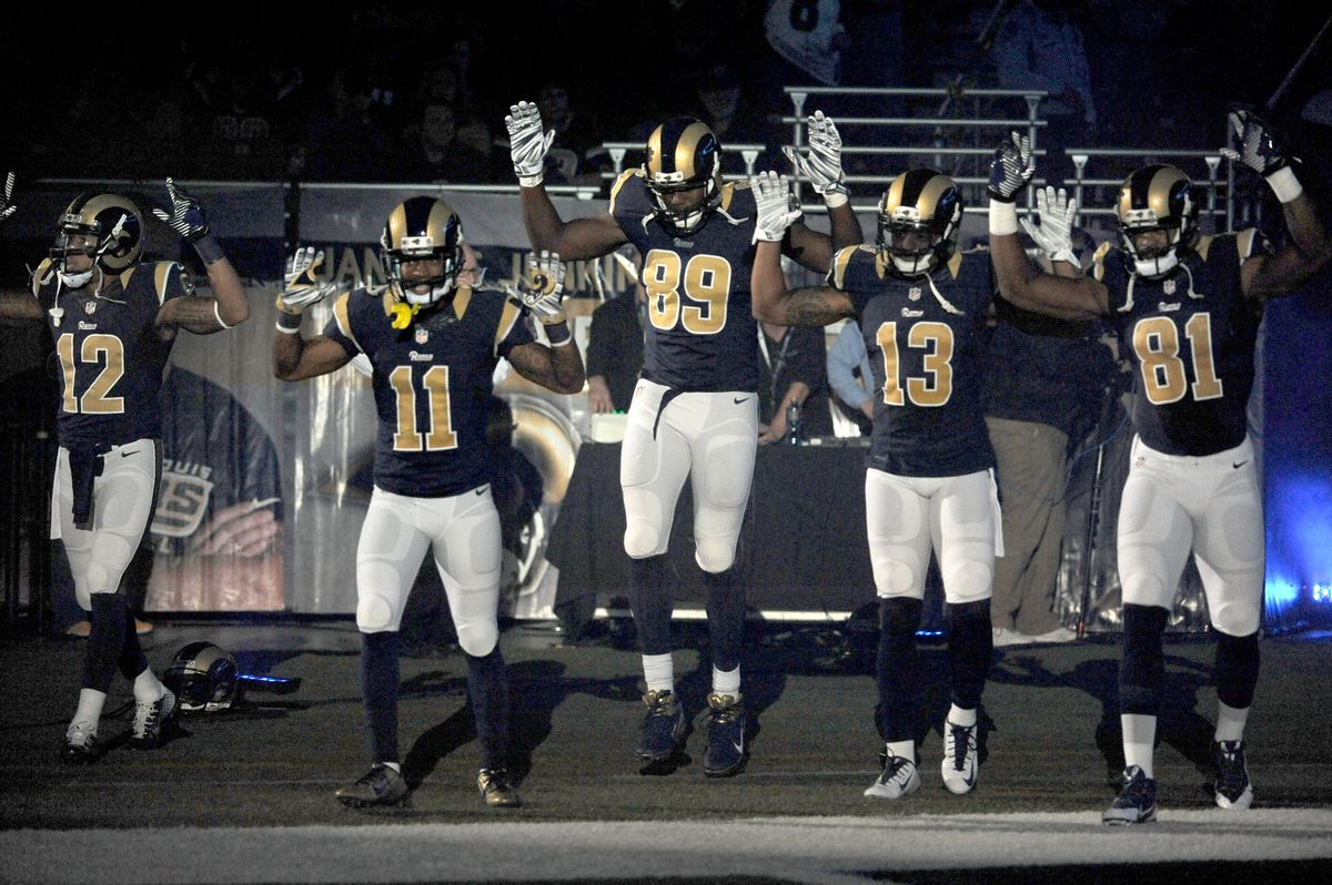 Members of the St. Louis Rams raise their arms in awareness of the events in Ferguson, Mo.,  as they walk onto the field during introductions before an NFL football game against the Oakland Raiders, Sunday, Nov. 30, 2014, in St. Louis.     (AP/L.G. Patterson)