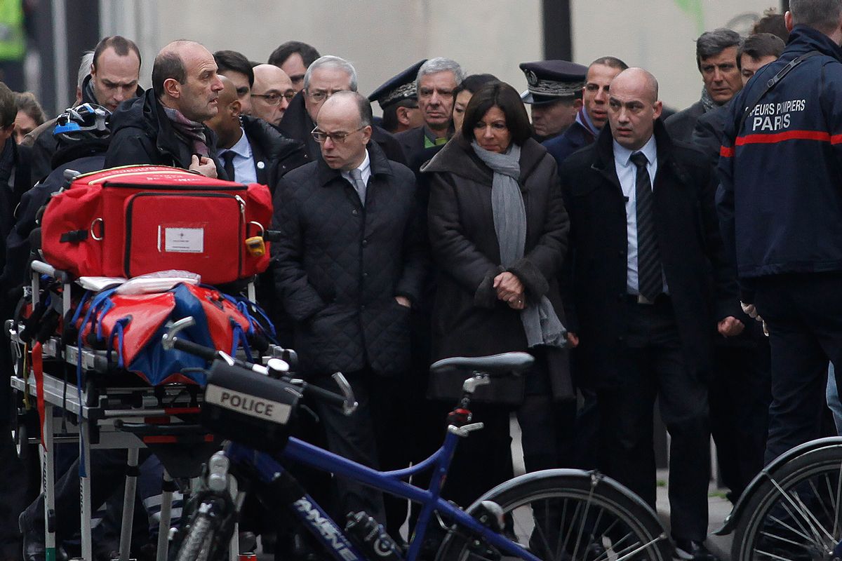 French Interior Minister Bernard Cazeneuve, center left, and Paris' mayor Anne Hidalgo, center right, arrive at the French satirical newspaper Charlie Hebdo's office, in Paris, Wednesday, Jan. 7, 2015. Masked gunmen stormed the offices of a French satirical newspaper Wednesday, killing at least 11 people before escaping, police and a witness said. The weekly has previously drawn condemnation from Muslims.  (AP Photo/Thibault Camus)