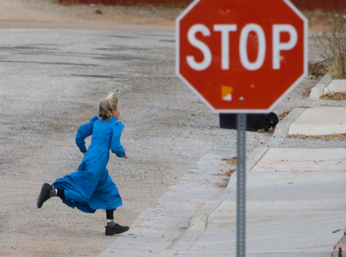In this Dec. 16, 2014 photo, a girl runs past a street sign in Hildale, Utah. The sister cities of Hildale and Colorado City, Ariz., once run by polygamist leader Warren Jeffs, are split between loyalists who still believe he is a victim of religious persecution and defectors who are embracing government efforts to pull the town into modern society. (AP Photo/Rick Bowmer) (AP)