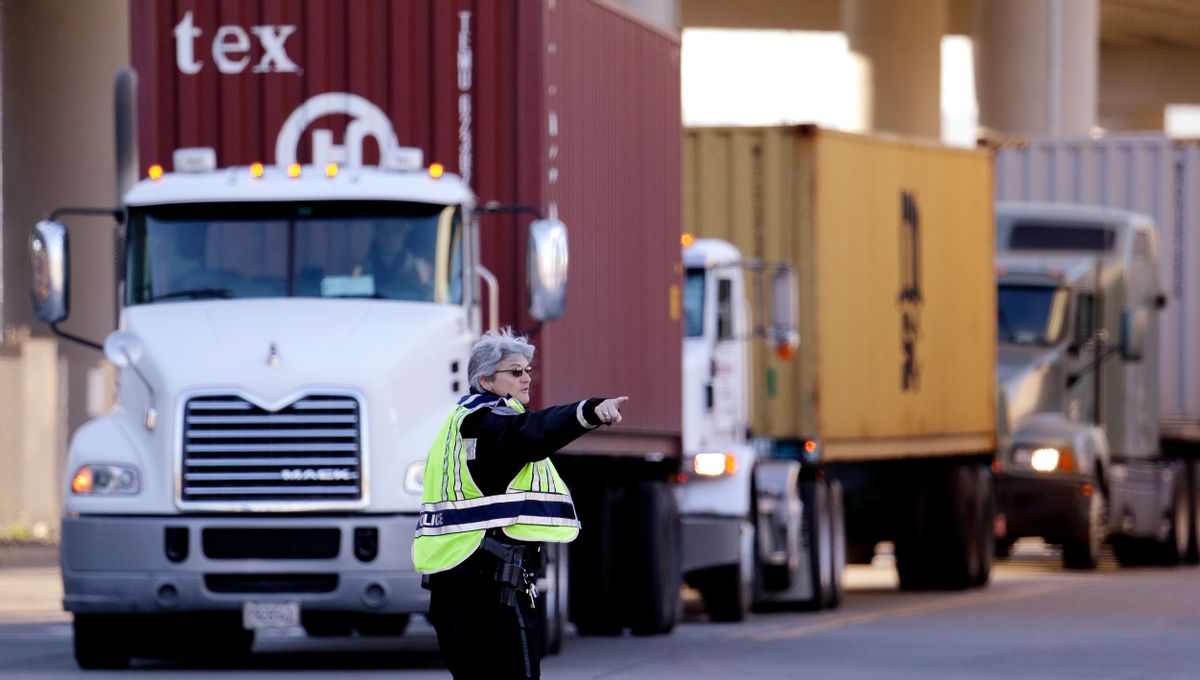 Seattle police officer Carol Castellani directs loaded container trucks to an entrance at the Port of Seattle Tuesday, Feb. 17, 2015, in Seattle. (AP Photo/Elaine Thompson) (AP)