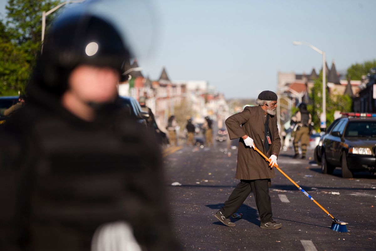 Residents clean streets as law enforcement officers stand guard, Tuesday, April 28, 2015, in Baltimore, in the aftermath of rioting following Monday's funeral of Freddie Gray, who died in police custody. (AP Photo/Matt Rourke)    (AP)