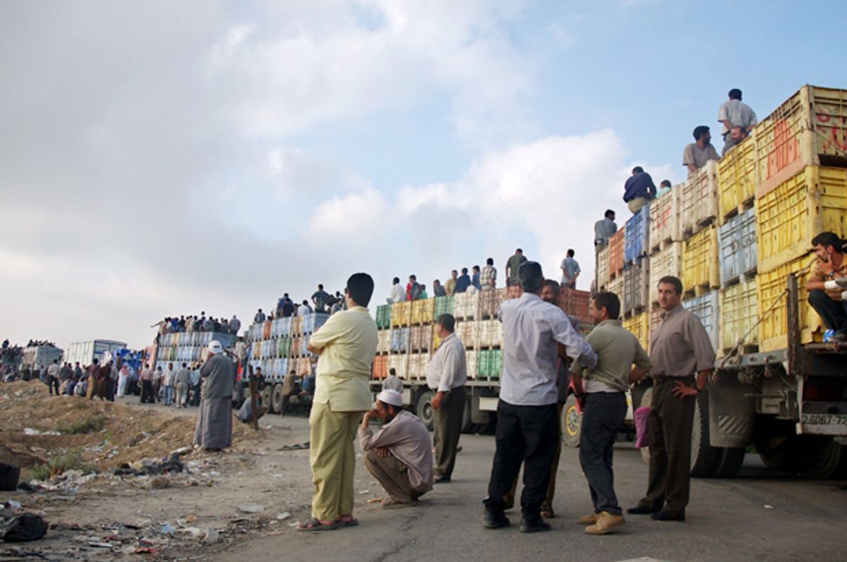 Palestinians wait in line with their vehicles to pass through the Abu Holi checkpoint in the central Gaza Strip, July 3, 2004.      (AP/Hatem Moussa)