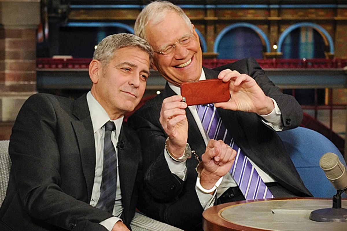 George Clooney handcuffs himself to David Letterman, Thursday May 14, 2015.            (CBS/Jeffrey R. Staab)