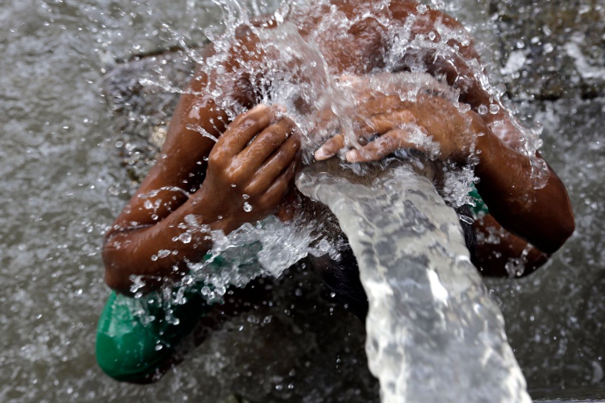 An Indian man bathes in water from a roadside tap in Kolkata, India, Sunday, May 31, 2015. Heat-related conditions, including dehydration and heat stroke, have killed more than 2,000 people since mid-April in the southern Indian states of Andhra Pradesh and Telangana, according to state officials. (AP Photo/ Bikas Das)  (Bikas Das)