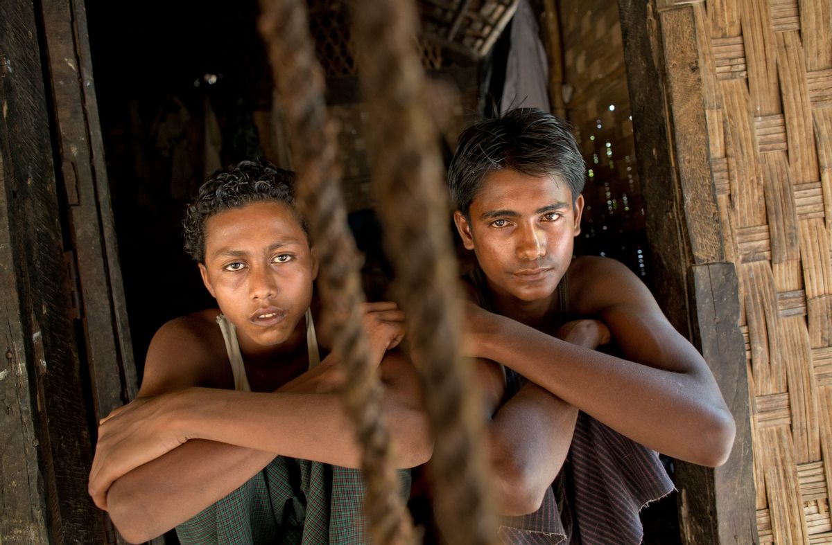 In this Monday, May 11, 2015, photo 16-year-old Sadik Hussein, left, and 17-year-old Noor Alam, hours after returning to their homes in Thetkabyin Village, north of Sittwe, western Rakhine state, Myanmar. They say they escaped from a human trafficking boat, where they sat for days with their knees bent into their chest, pressed up against other sweaty bodies in the cabins rancid heat. They say members of the crew paced back and forth with iron rods and belts, hitting anyone who dared speak or even vomit from the nauseating stench and rolling waves. (AP Photo/Gemunu Amarasinghe) (AP Photo/Gemunu Amarasinghe)