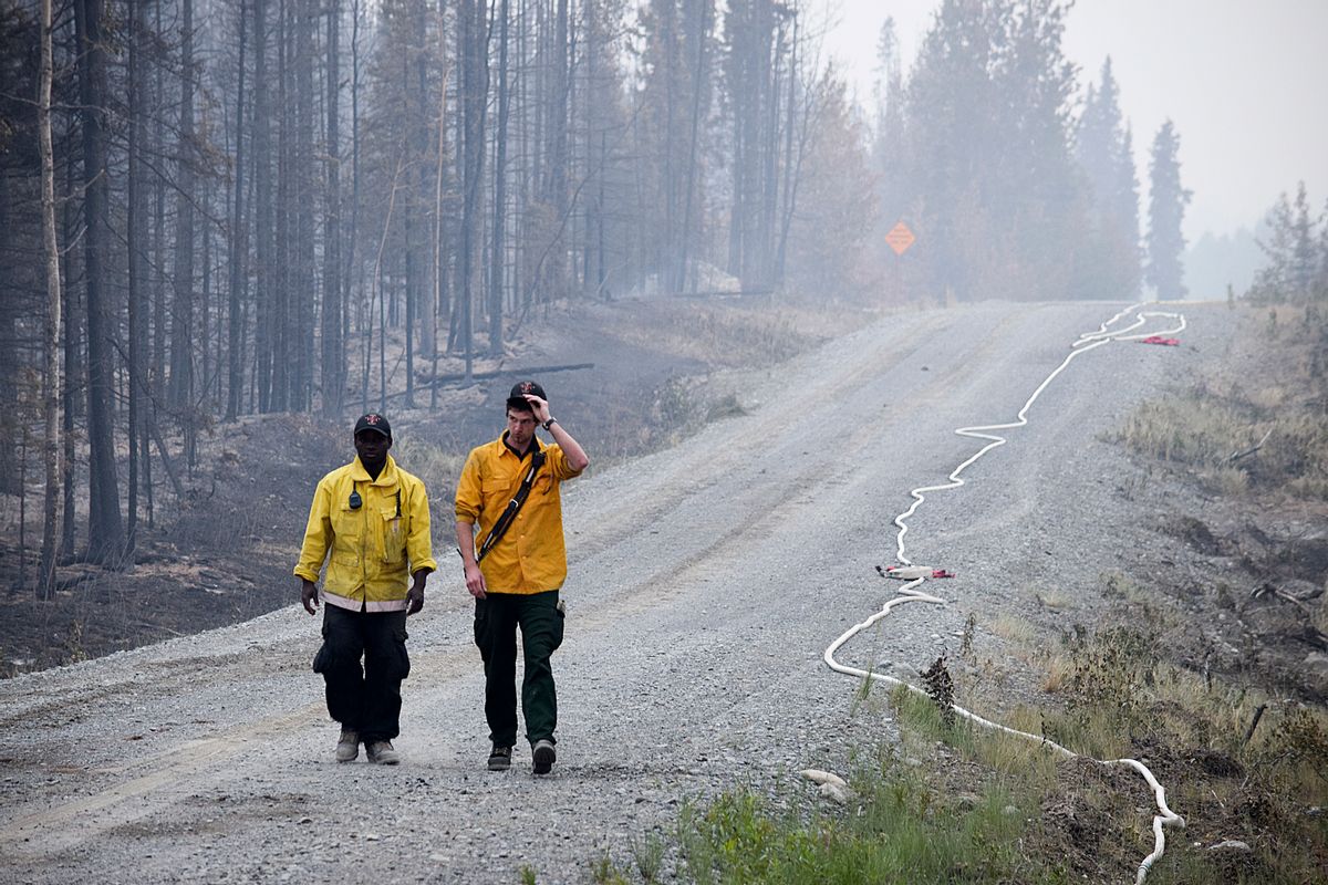 In this June 16, 2015 photo, two Nikiski Fire Department firefighters walk on a road near a fire-ravaged forest left behind by the Card Street fire in Sterling, Alaska. The wildfire moved rapidly northeast toward the Kenai National Wildlife Refuge and authorities have evacuated the Upper and Lower Skilak Lake campground. (Rashah McChesney/Peninsula Clarion via AP)  (AP)