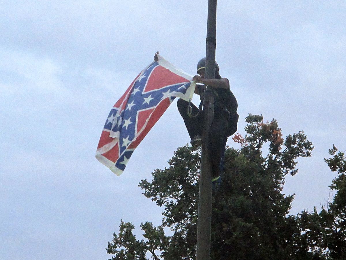 Bree Newsome of Charlotte, N.C., removes the Confederate battle flag at a Confederate monument at the Statehouse in Columbia, S.C. She was taken into custody when she came down. The flag was raised again by capitol workers about 45 minutes later.   (AP Photo/Bruce Smith)