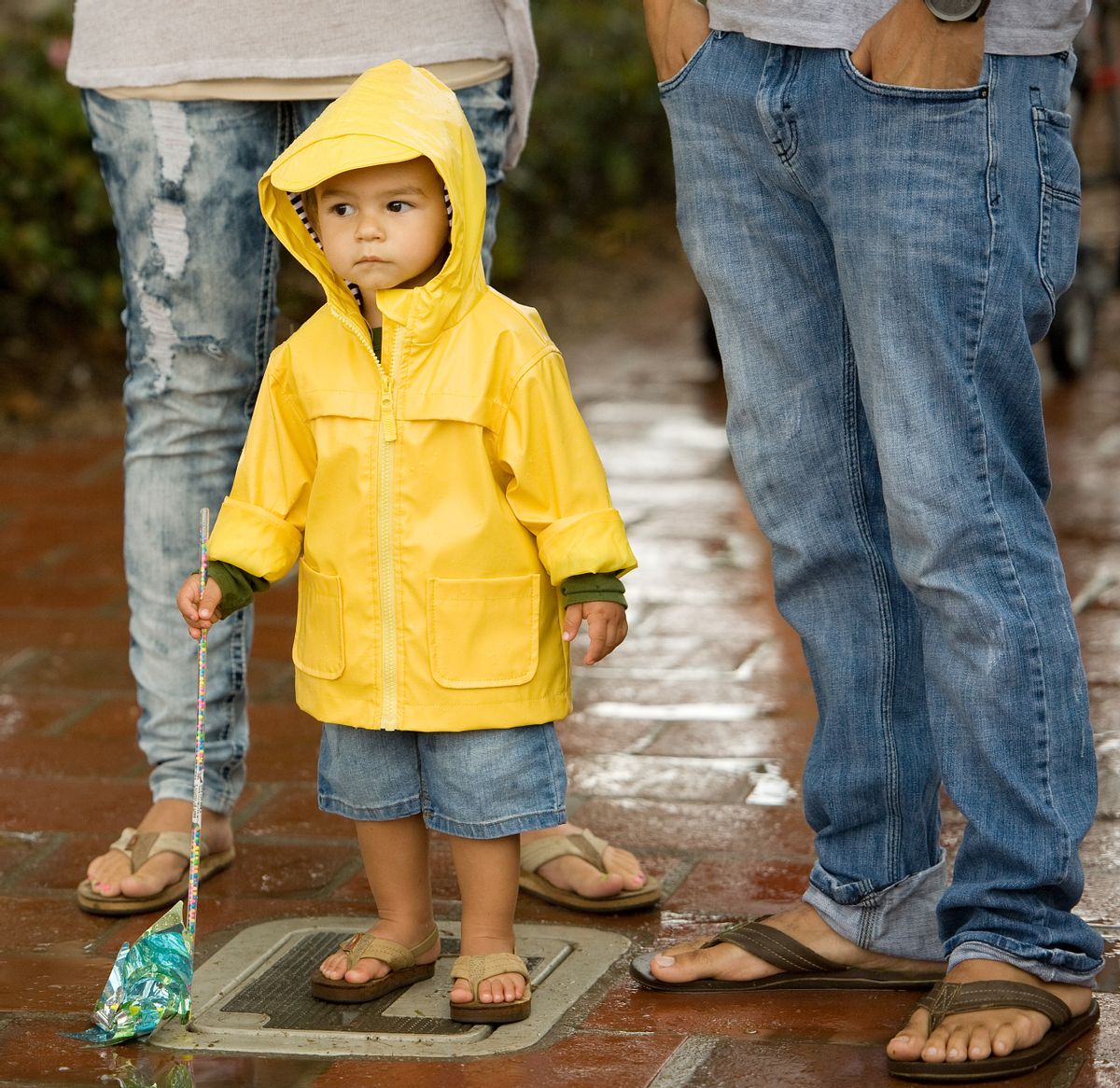 Ezekiel Ekinaka, 1, with his parents Aaron and Juliet, wears a raincoat as he experiences rain for the second time in his life, at the San Clemente, Calif. Ocean Festival before the public was urged to evacuate due to lightning on Saturday, July 18, 2015. (Mindy Schauer/The Orange County Register via AP)  (AP)