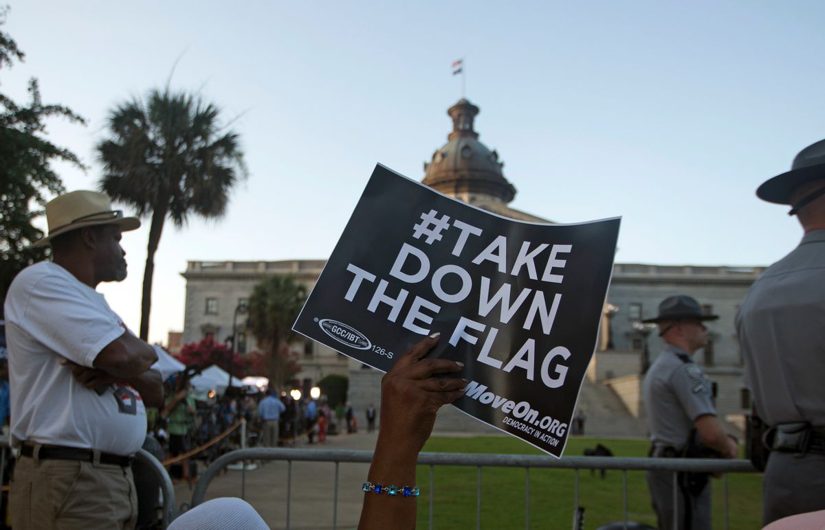 A woman waves a sign as she waits for the Confederate battle flag to be removed from in front of the South Carolina Statehouse, Friday, July 10, 2015, in Columbia, S.C.  (AP Photo/John Bazemore)