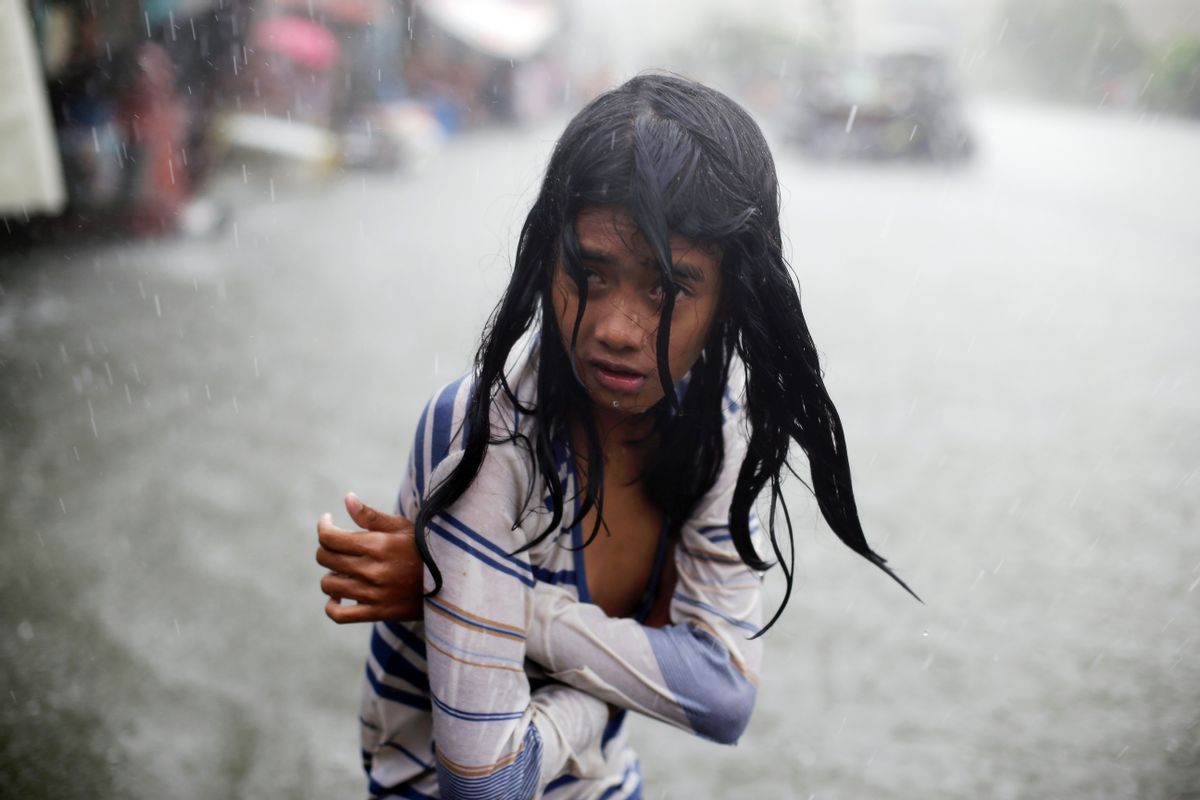 A Filipino girl tries to keep herself warm as she wades in floodwaters in the coastal village of Malabon, north of Manila, Philippines on Wednesday, July 8, 2015. Typhoon Chan-Hom is passing over the northeastern waters of the Philippines and heading to northern Taiwan, dumping heavy rains over the capital, Manila, and the northern provinces. (AP Photo/Aaron Favila)FILE- (Aaron Favila)