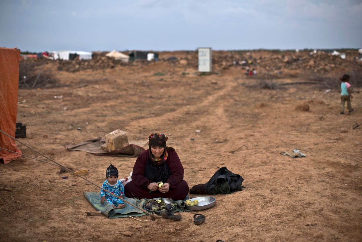 FILE-- In this Oct. 28, 2015 file photo, a Syrian refugee child sits next to his grandmother while peeling eggplant for dinner, outside their tent at an informal tented settlement near the Syrian border on the outskirts of Mafraq, Jordan. The number of Syrian refugees stranded in a remote desert area known as "the berm," on the Jordanian border has tripled to 12,000 since last month, the U.N. refugee agency said Tuesday, Dec. 8, 2015. (AP Photo/Muhammed Muheisen, File) (AP)