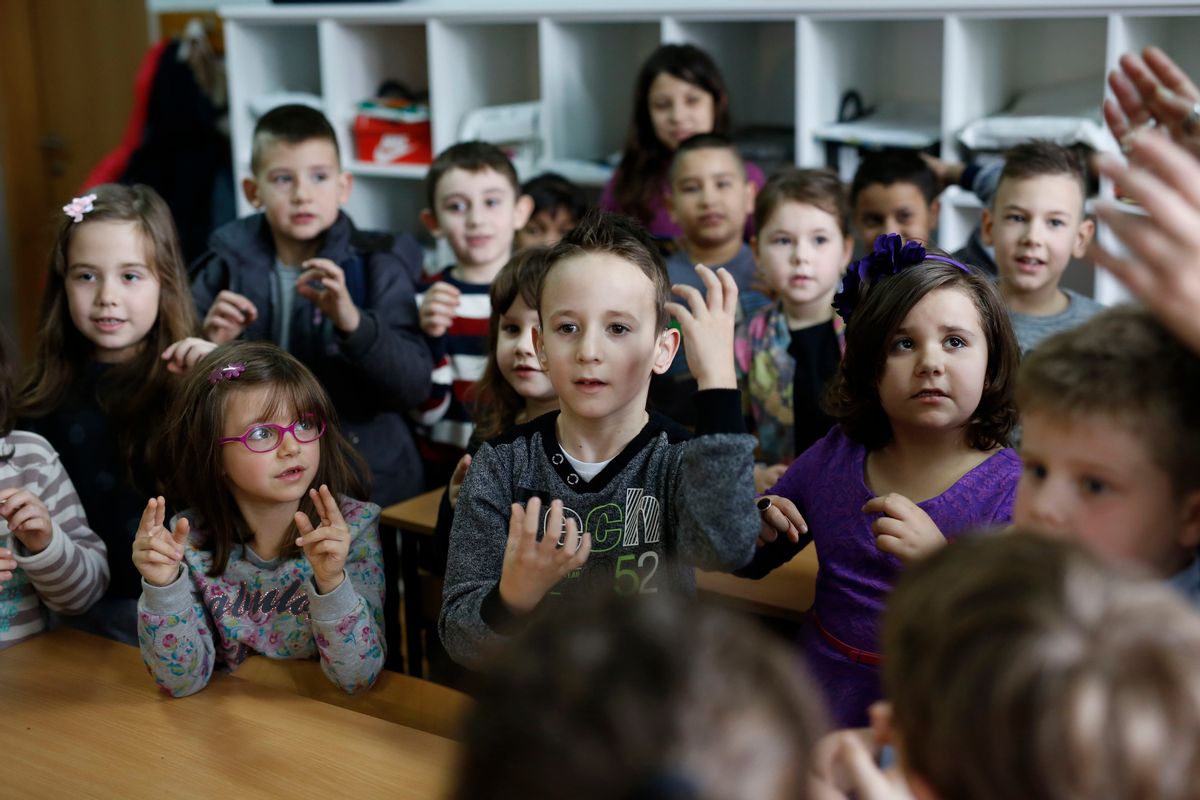 In this photo taken Thursday, Feb. 4, 2016, Bosnian boy Zejd Coralic, center, learns sign language from teacher Anisa Setkic-Sendic, not shown, with other children in a class at an elementary school in Sarajevo, Bosnia. I (AP)