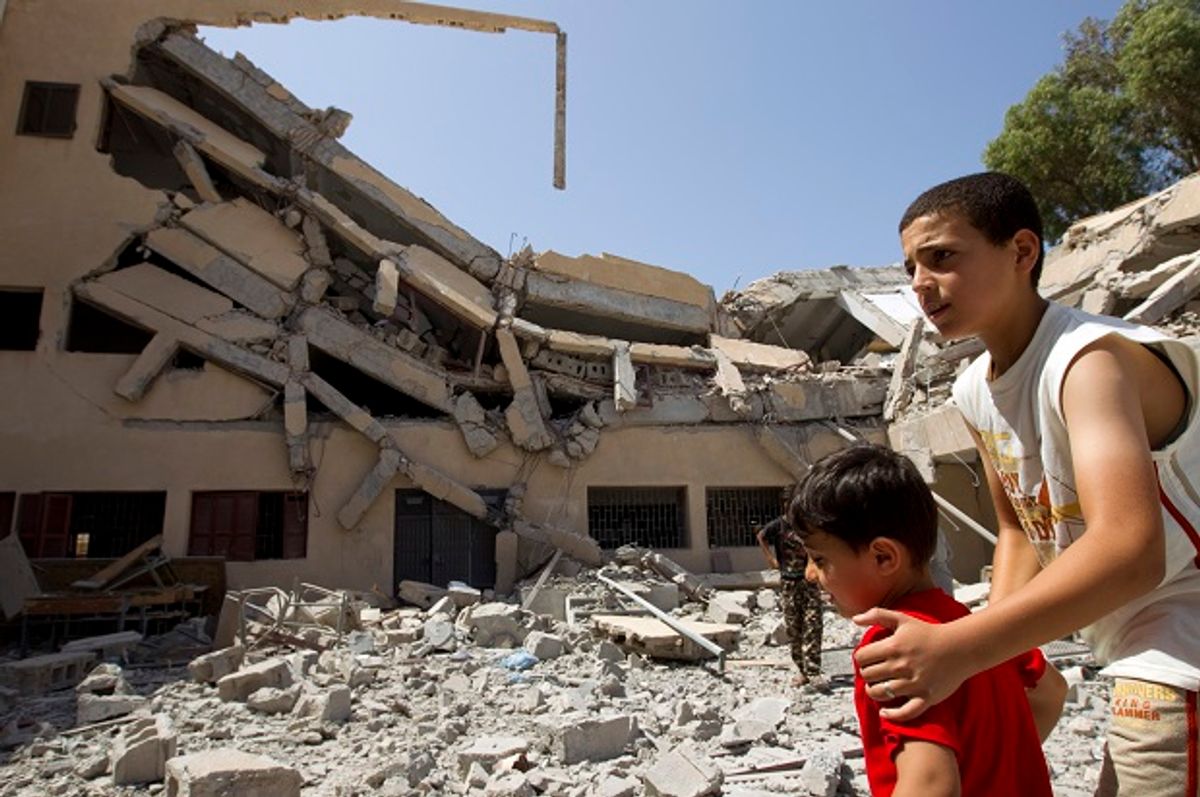 Libyan boys walk near the wreckage of a school bombed by NATO forces in August 2011  (Reuters/Caren Firouz)