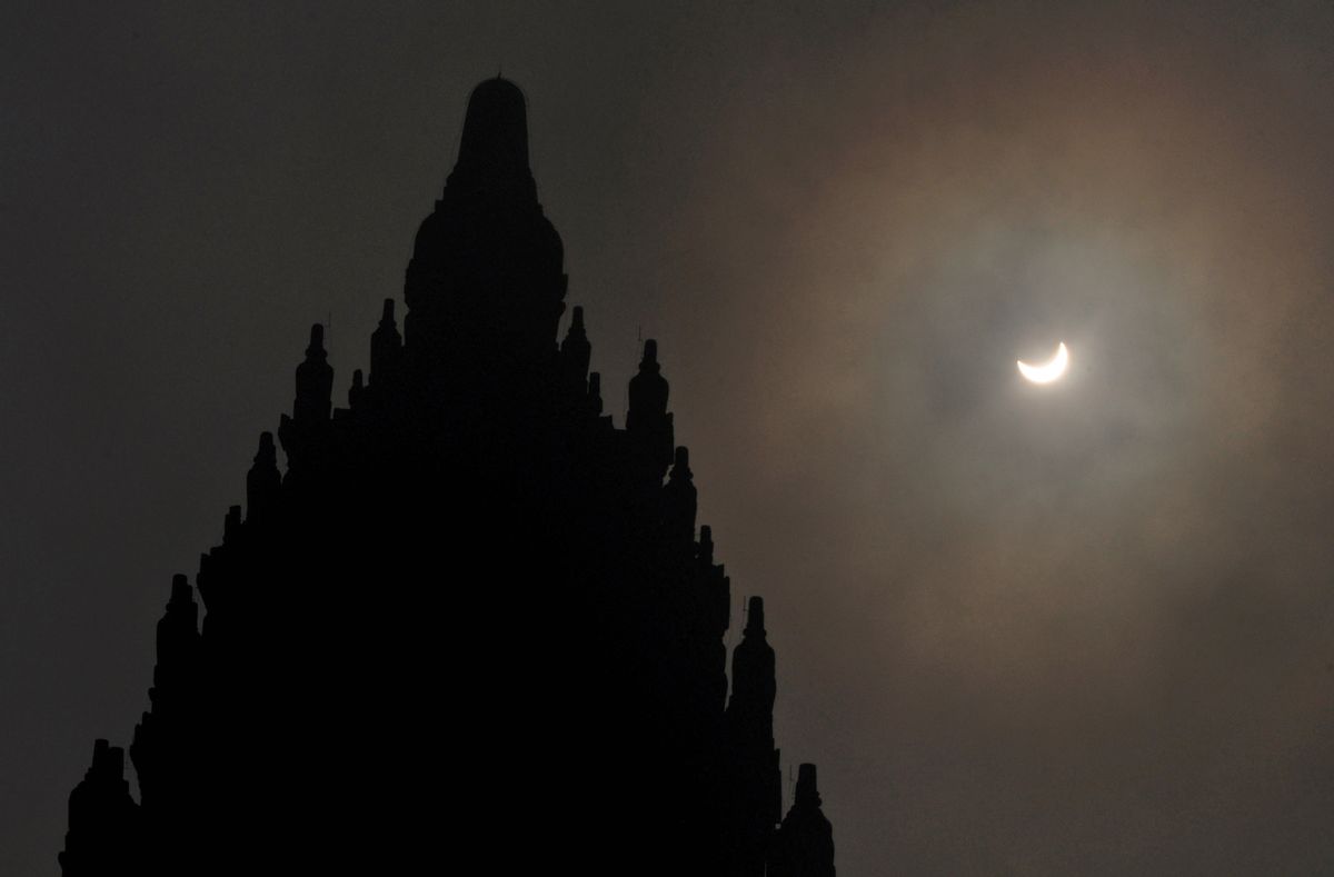 A partial solar eclipse is seen behind the 9th century Prambanan Temple in Yogyakarta, Indonesia, Wednesday, March 9, 2016. The rare astronomical event is being witnessed Wednesday along a narrow path that stretches across 12 provinces encompassing three times zones and about 40 million people. (AP Photo/Slamet Riyadi) (AP)