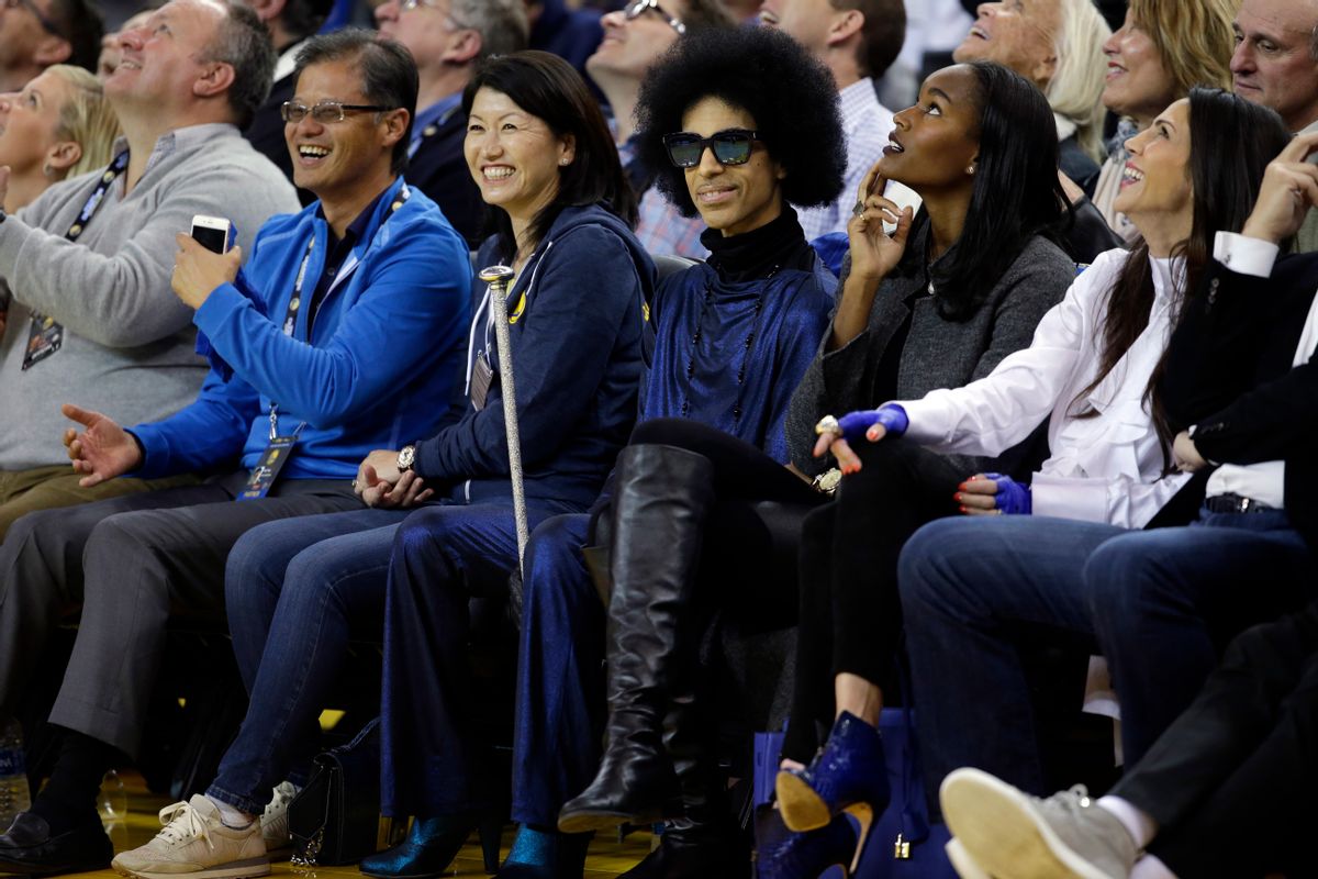 Singer Prince, center, smiles as he watches an NBA basketball game between the Golden State Warriors and the Oklahoma City Thunder Thursday, March 3, 2016, in Oakland, Calif. (AP Photo/Marcio Jose Sanchez) (AP)