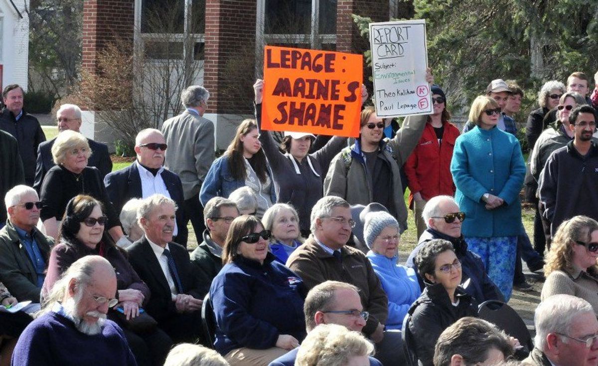 University of Maine at Farmington students Allyson Hammond, left, and Nickolas Bray hold up posters critical of Gov. Paul LePage during the dedication of the Theodora J. Kalikow Education Center on Tuesday. (Morning Sentinel: David Leaming)