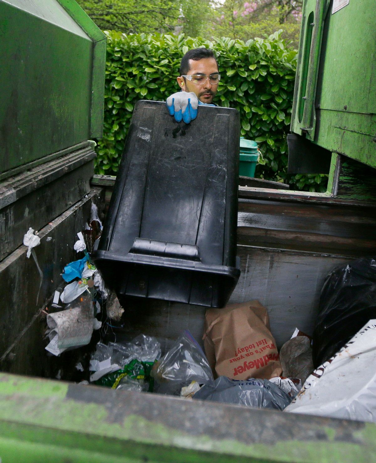 David Morales, a garbage driver with Recology, dumps a garbage container for Seattle Public Utilities, Friday, April 15, 2016, in Seattle. A judge is scheduled to hear a challenge Friday, April 16, 2016, to a new Seattle law allowing garbage collectors to check people's trash to see whether they are disposing of recycling items and food waste incorrectly.  (AP Photo/Ted S. Warren) (AP)