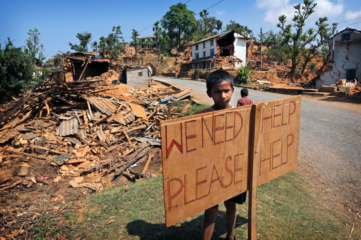 FILE - In this May 2, 2015 file photo, a Nepalese boy stands outside his village with a signboard asking for help in Pauwathok village, Sindhupalchok district, Nepal. A year after a set of devastating earthquakes plunged Nepal into chaos and economic decline, one question remains on everyones mind: what if it happens again? Scientists have been warning Nepal and other Himalayan countries for years that quake risks in the region are high. But while citizens are preparing for the worst by building sturdier homes and stockpiling emergency supplies, experts say officials still have a long way to go in preparing for possible, if not probable, disaster. (AP Photo/Manish Swarup, File) (AP)