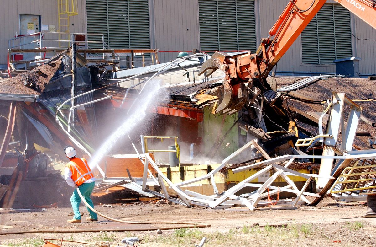 FILE--In this July 15, 2004, file photo a worker sprays water to keep down the dust as a giant claw on an excavator rips apart Building 771 at the former Rocky Flats nuclear weapons plant near Golden, Colo. Attorneys say they reached a $375 million settlement late Wednesday, May 18, 2016, in a legal battle between the operators of the former nuclear weapons plant outside Denver and thousands of homeowners who said plutonium releases from the plant hurt their property values.  It must still be approved by a federal judge, and it could take months to set up a process for homeowners to file claims. (AP Photo/Ed Andrieski, file) (AP)