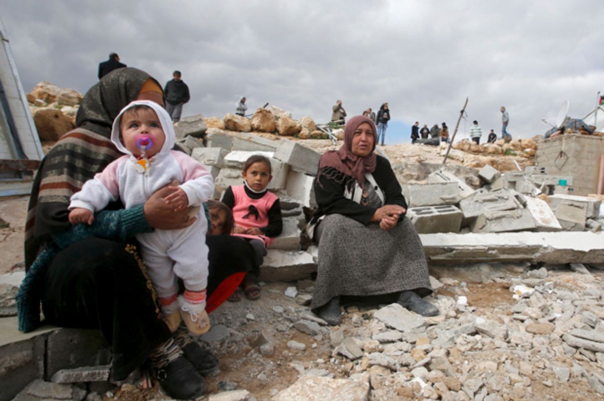 Palestinians sit among the rubble of their house, which was demolished by Israeli bulldozers, in the West Bank village of Jimba, February 2, 2016.   (Reuters/Mussa Qawasma)