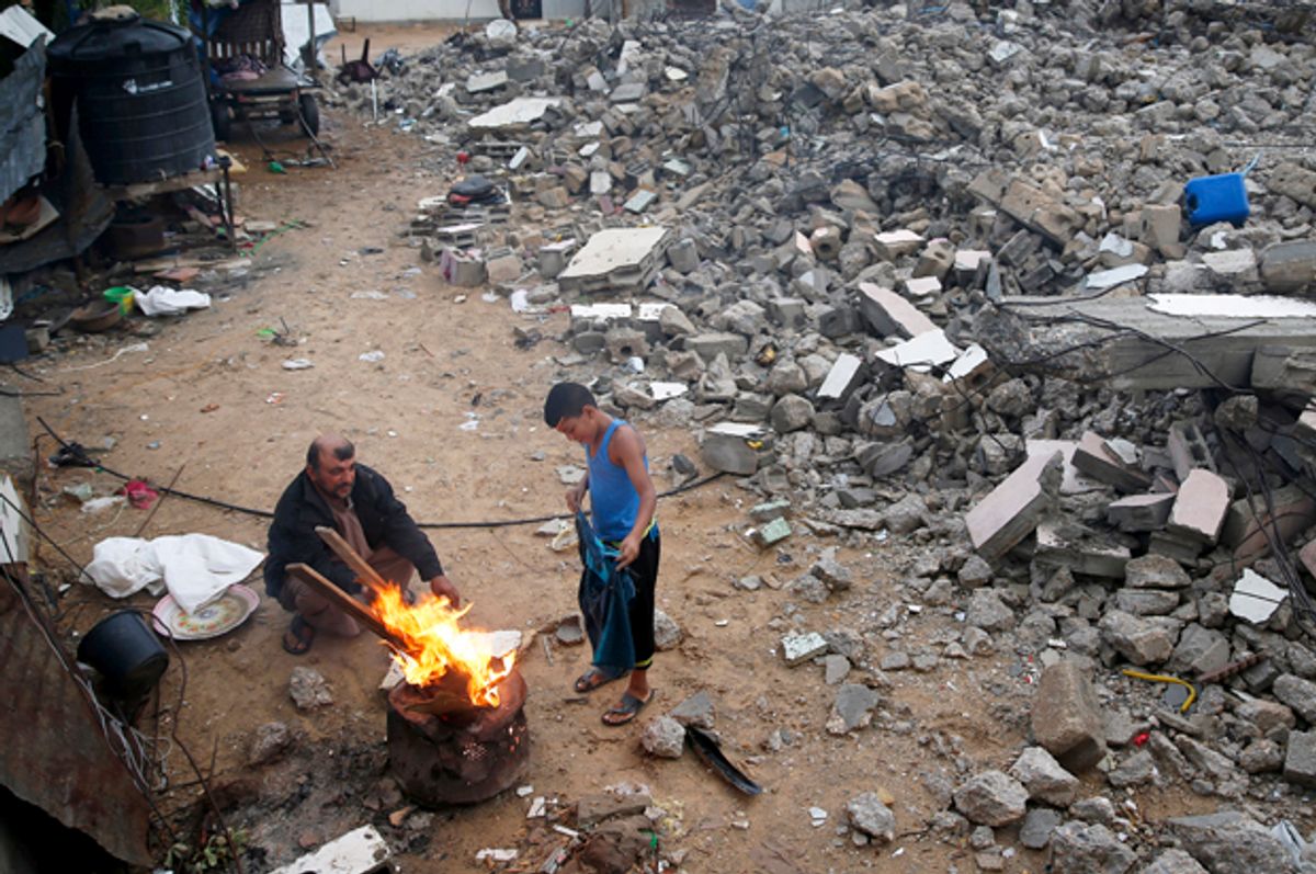 A Palestinian boy dries his shirt near a fire, amongst ruins in Gaza City, October 7, 2015.    (Reuters/Suhaib Salem)