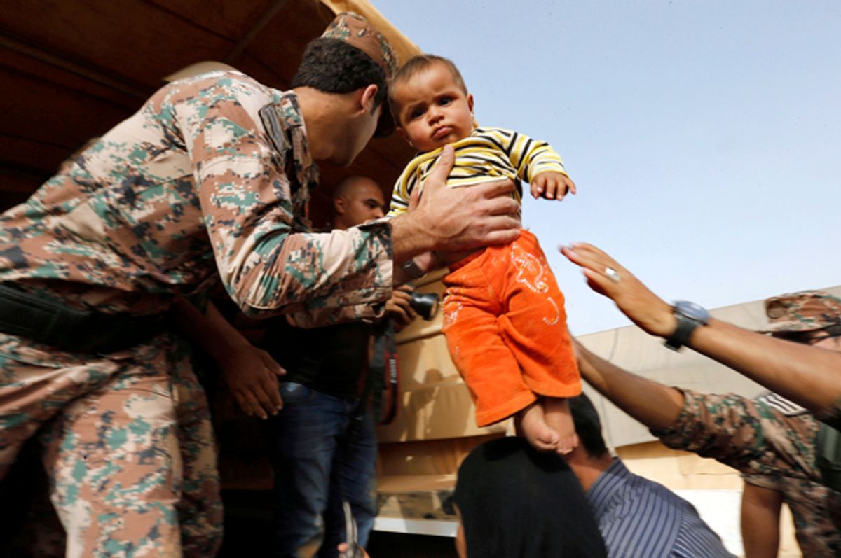 A Jordanian soldier carries a Syrian refugee child to help him board a Jordanian army vehicle with his family near Ruwaished, Jordan, September 10, 2015.   (Reuters/Muhammad Hamed)