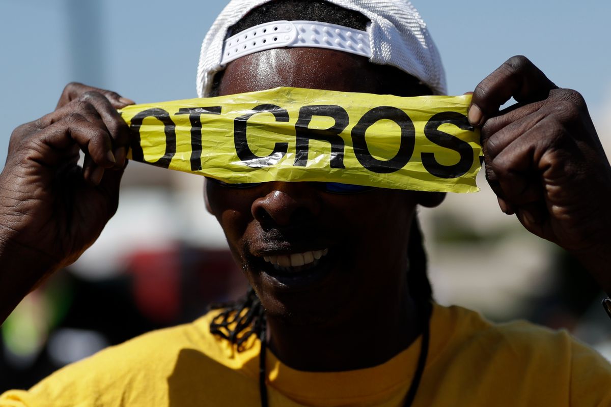 A man covers his eyes with police tape during a protest, Wednesday, Sept. 28, 2016, in El Cajon, Calif. Dozens of demonstrators on Wednesday protested the killing of a black man shot by an officer after authorities said the man pulled an object from a pocket, pointed it and assumed a "shooting stance." (AP Photo/Gregory Bull) (AP)