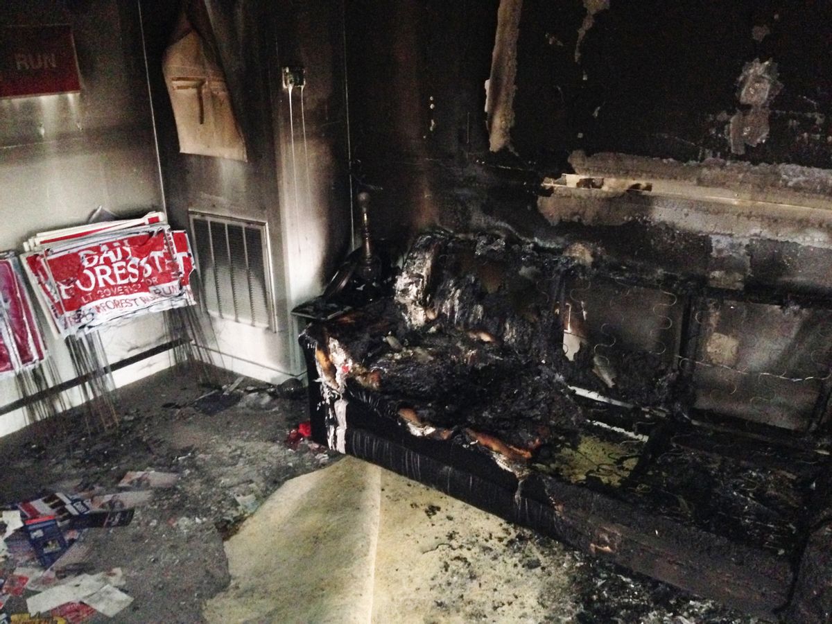 A burned couch is shown next to warped campaign signs at the Orange County Republican Headquarters in Hillsborough, NC on Sunday, Oct. 16 2016. (AP)