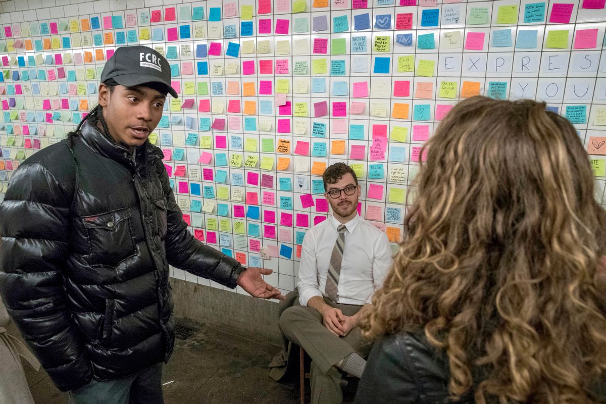 Matthew Chavez, center, who goes by the artist name Levee, talks to commuters about the messages posted on the "Subway Therapy" wall, Friday, Nov. 11, 2016, in New York. Levee started the installation in the underground passageway that connects the 1 train to the L train on 14th St., where people are encouraged to leave their feelings about the presidential election written on Post-It notes. (AP Photo/Mary Altaffer) (AP)