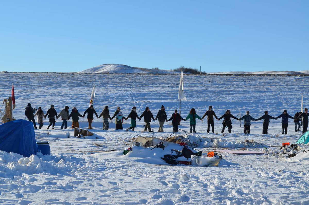 Many join hands in prayer at Oceti Sakowin camp shortly before the decision to halt the pipeline was announced. (Charlie May)