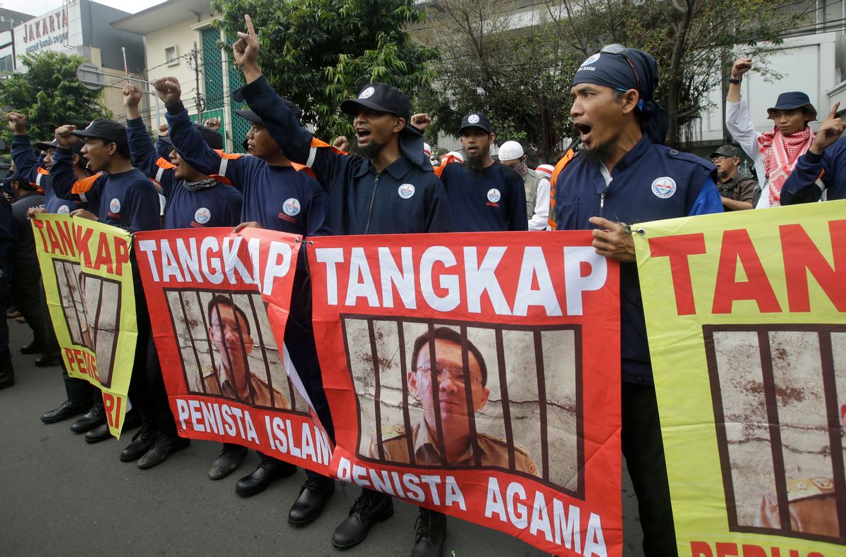 Protesters display posters of Jakarta Governor Basuki Tjahaja Purnama, popularly known as "Ahok," with writings that read: "Arrest blasphemer" during his trial hearing at a district court in Jakarta, Indonesia, Tuesday, Dec. 13, 2016.  (AP Photo/Achmad Ibrahim)
