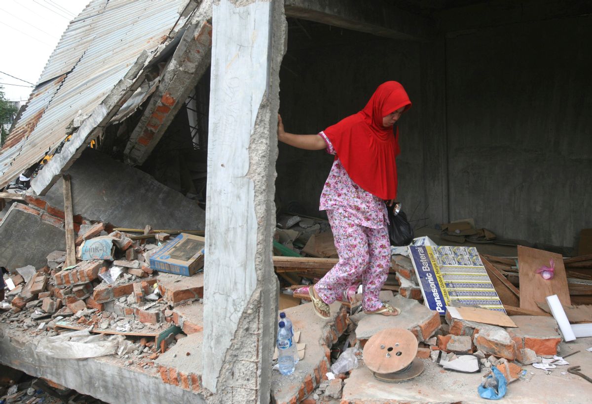 Earthquake survivor Fakriyah tries to balance herself as she walks on the rubble at her shop damaged during Wednesday's earthquake in Tringgading, Aceh province, Indonesia, Friday, Dec. 9, 2016. Over a hundred people were killed in the quake that hit the northeast of the province on Sumatra before dawn Wednesday. Hundreds of people were injured and thousands buildings destroyed or heavily damaged. (AP Photo/Binsar Bakkara) (AP)