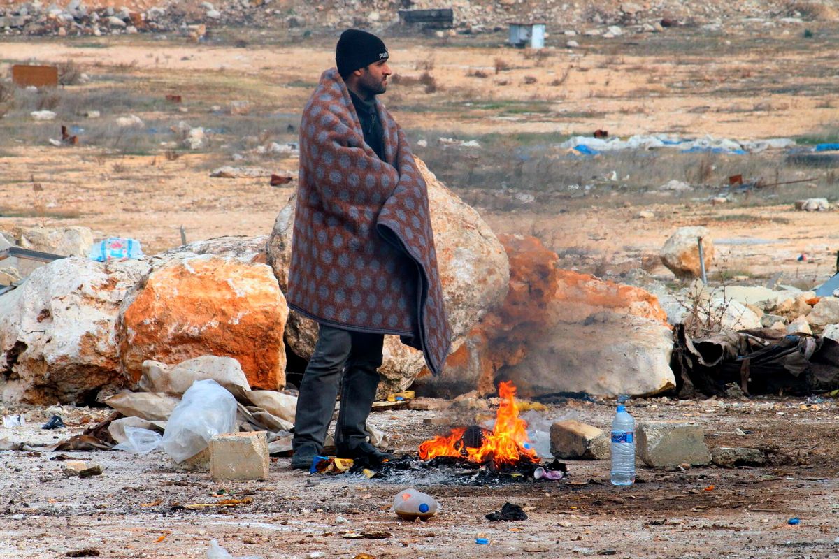 This image released on Friday, Dec. 16, 2016 by Aleppo 24, shows a man of eastern Aleppo standing next to a fire in western rural Aleppo, Syria. As the last holdouts leave the rebel-held enclave in Aleppo, they speak of their love for the city despite witnessing so much destruction and death. Bit by bit over three weeks, the government offensive chipped away at their last refuge. (Aleppo 24 via AP) (AP)