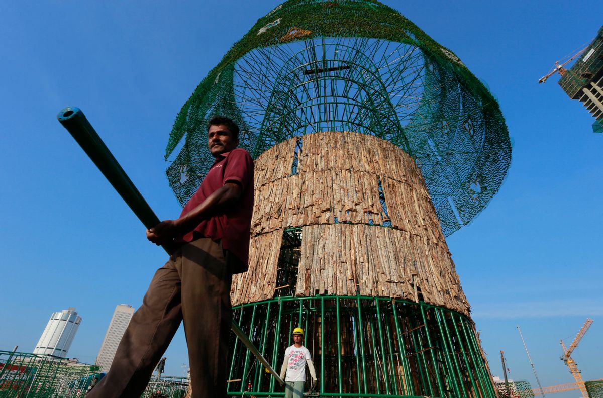 In this Thursday, Dec. 15, 2016 photo, Haloluwage Don Nanayakkara, left, carries a steel rod with another worker as they try to build an enormous, artificial Christmas tree on a popular beachside promenade in Colombo, Sri Lanka. The idea for the tree came from this Buddhist driver at Colombo’s port who makes decorations in his spare time. Hundreds of Sri Lanka’s port workers and volunteers are struggling to put up the towering Christmas tree in time for the holidays. The majority-Buddhist nation is aiming to beat the world record for the tallest, artificial Christmas tree as a show of multicultural respect. But twice the construction deadline was missed, and now organizers hope to erect the tree on Christmas Eve. The Catholic Church has criticized the $80,000 price tag as a waste of money that is better spent helping the poor. (AP Photo/Eranga Jayawardena) (AP)
