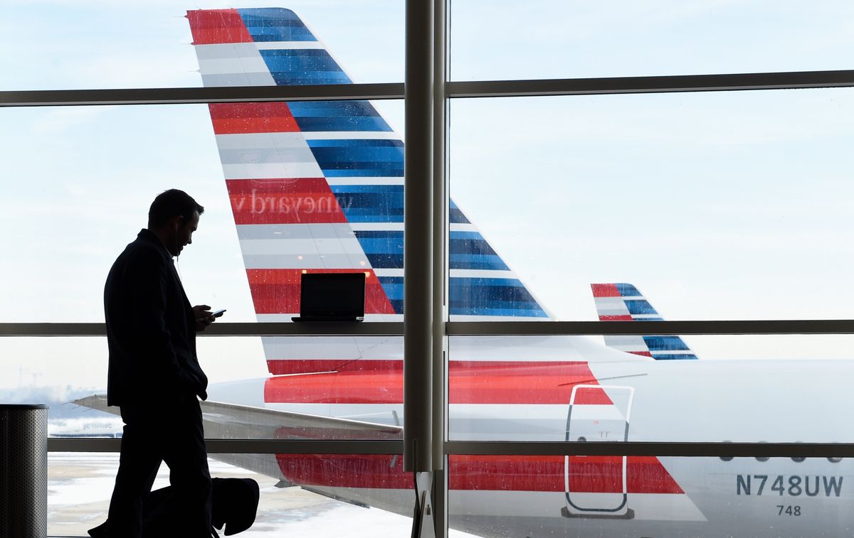 FILE - In this Jan. 25, 2016, file photo, a passenger talks on the phone as American Airlines jets sit parked at their gates at Washington's Ronald Reagan National Airport. American Airlines announced Wednesday, Jan. 18, 2017, that passengers will be able to buy “basic economy” tickets starting in February that will be similar to bare-bones fares already offered by Delta Air Lines and soon to be matched by United Airlines. The basic-economy fares will have a lower price, but will offer fewer comforts. (AP Photo/Susan Walsh, File) (AP)