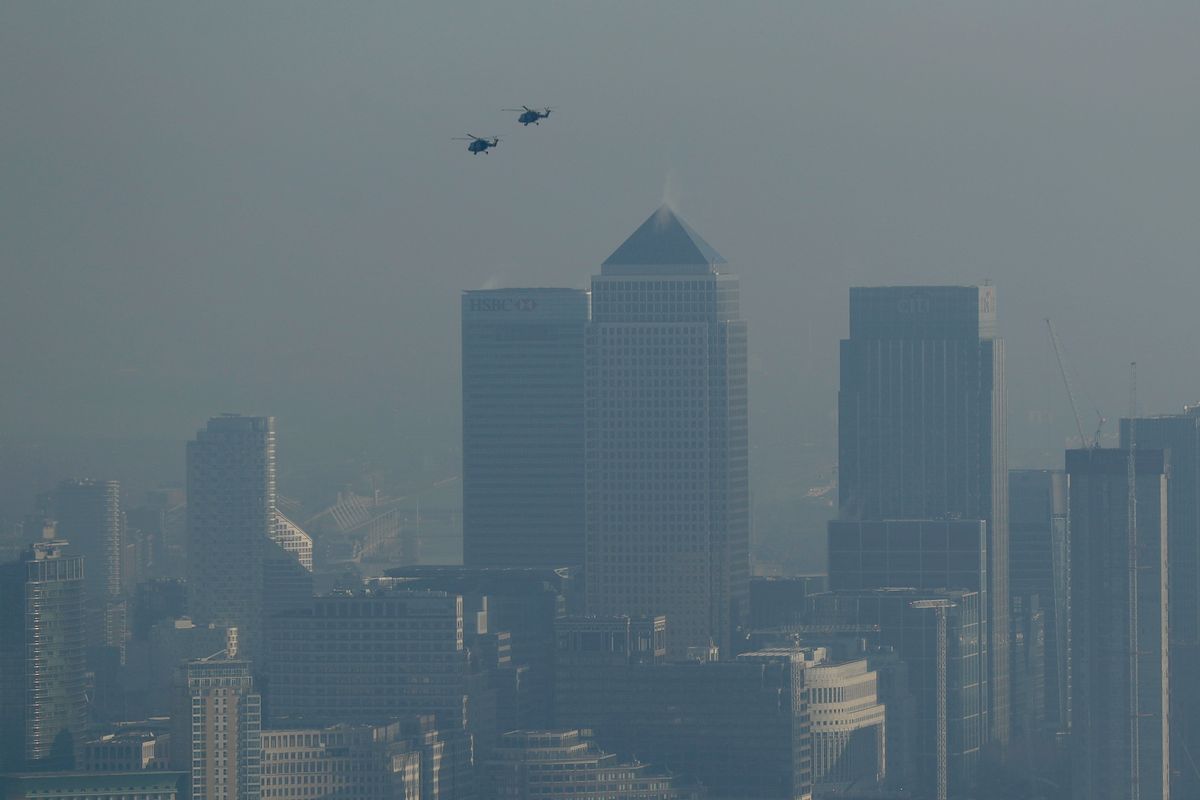 Helicopters fly through pollution over the Canary Wharf business district through a window in a viewing area of the 95-storey skyscraper The Shard, the tallest building in Britain at 309.6 metres, in London, Thursday, Jan. 19, 2017. Eight London boroughs issued high pollution warnings Thursday. (AP Photo/Matt Dunham) (AP)