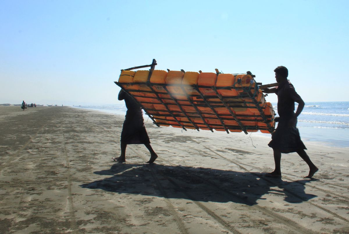 In this Jan. 16, 2017, photo, Rohingya fishermen carry a fishing raft, constructed with empty plastic containers, up the beach in Tha Pyay Taw village, Maungdaw, western Rakhine state, Myanmar. (AP Photo/Esther Htusan) (AP)