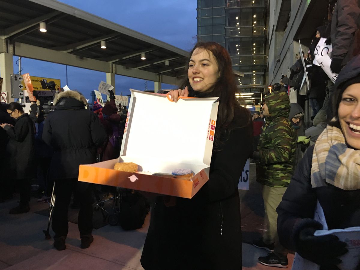A woman hands out free donuts to protesters gathered at JFK airport to protest Donald Trump's anti-immigration orders (Amanda Marcotte)