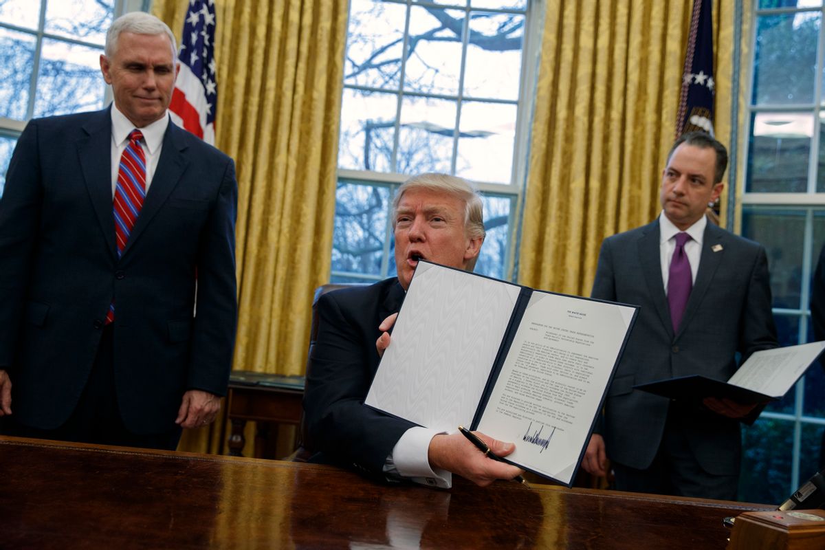Vice President Mike Pence, left, and White House Chief of Staff Reince Priebus watch as President Donald Trump shows off an executive order to withdraw the U.S. from the 12-nation Trans-Pacific Partnership trade pact agreed to under the Obama administration, Monday, Jan. 23, 2017, in the Oval Office of the White House in Washington. (AP Photo/Evan Vucci) (AP)