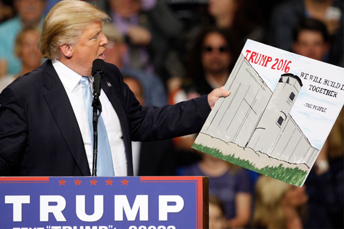 U.S. Republican presidential candidate Donald Trump holds a sign supporting his plan to build a wall between the United States and Mexico that he borrowed from a member of the audience at his campaign rally in Fayetteville, North Carolina March 9, 2016. Trump was interrupted repeatedly by demonstrators during his rally.    REUTERS/Jonathan Drake - RTSA418 (Reuters)