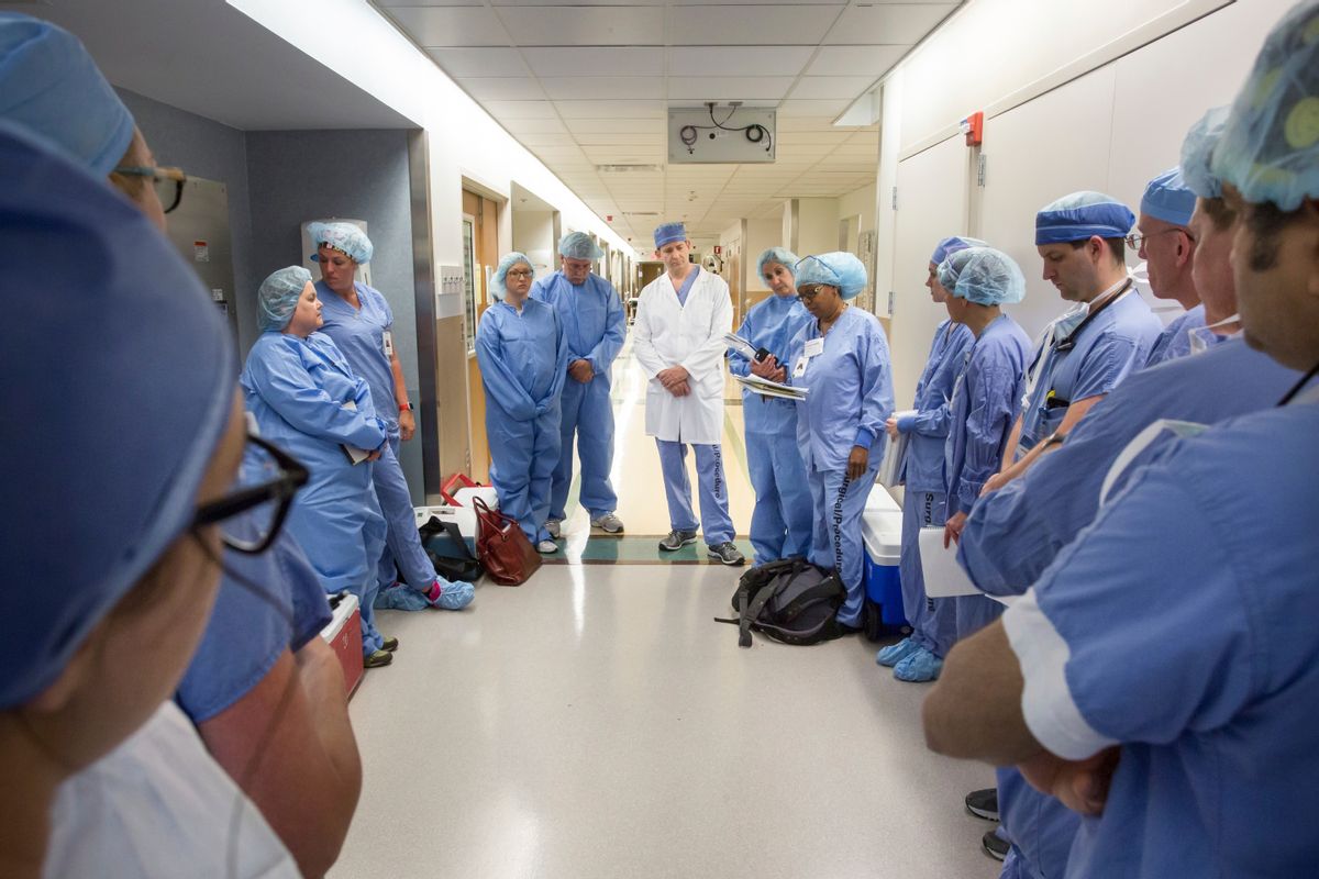 In this June 10, 2016 photo provided by the Mayo Clinic, a medical team of about 60 doctors, nurses, anesthesiologists and others at Mayo Clinic gather before performing the first face transplant surgery at their hospital in Rochester, Minn. Mardini and his team devoted more than 50 Saturdays over 3 1/2 years to rehearsing the procedure, using sets of cadaver heads to transplant the face of one to another. They used 3D imaging and virtual surgery to plot out the bony cuts so the donor's face would fit perfectly on Andy Sandness. (Michael Cleary/Mayo Clinic via AP) (AP)