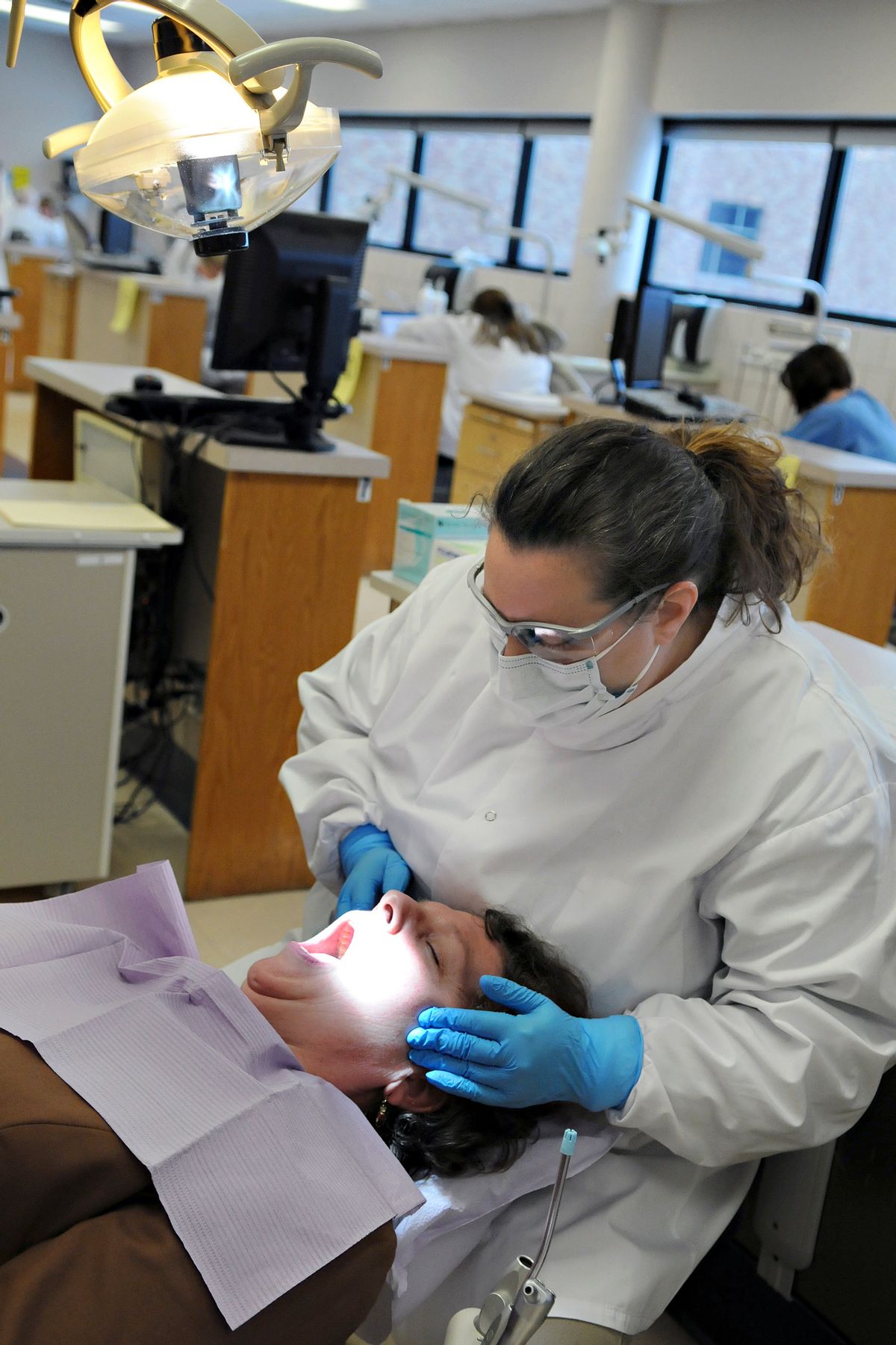 FILE - In this Dec. 4, 2009 file photo, dental hygienist Jodi Hager performs an oral exam on staff member Clare Larkin during a test at Normandale Community College in Edina, Minn. Several states are considering bills that would create a new midlevel position in dentistry called dental therapists or advanced dental hygiene practitioners. They can perform common procedures such as filling cavities or pulling teeth, though more complex procedures would still be left with dentists. (AP Photo/Dawn Villella, File) (AP)