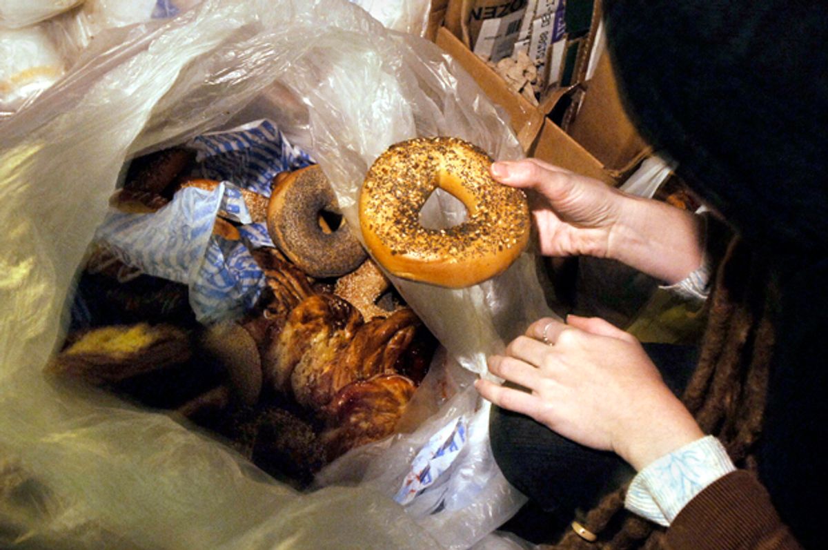 A woman holds a bagel she found in a garbage bag of pastries and bagels outside a shop in New York   (Getty/Stan Honda)