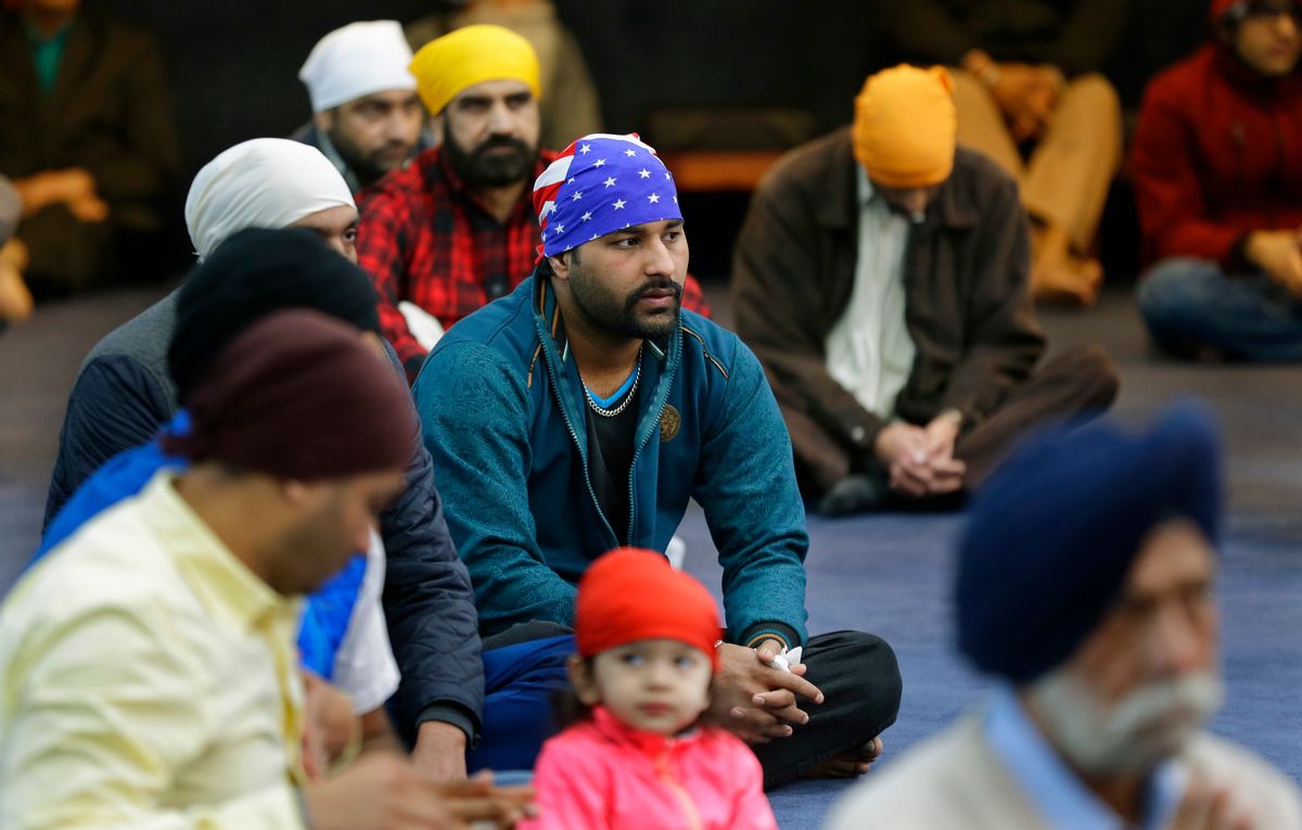Men, including one wearing a head covering with the stars and stripes of the U.S. flag, attend Sunday services at the Gurudwara Singh Sabha of Washington, a Sikh temple in Renton, Wash., Sunday, March 5, 2017, south of Seattle.  (AP Photo/Ted S. Warren)