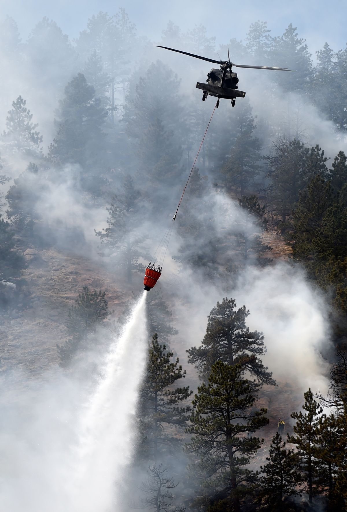 A helicopter drops water on the fire as crews battle the Sunshine Fire in the Sunshine canyon area of Boulder, Colo. on Sunday, March 19, 2017.  (Jeremy Papasso/Daily Camera via AP) (AP)