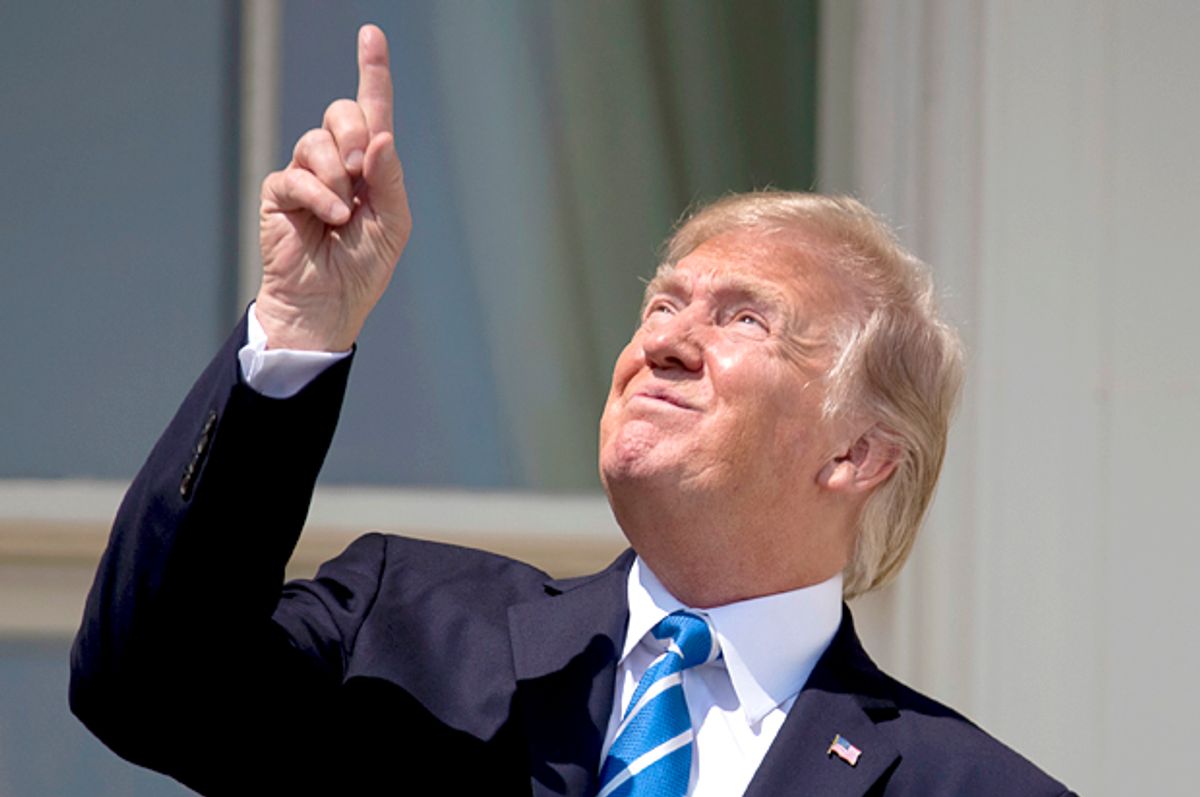 Donald Trump points to the sun as he arrives to view the solar eclipse. (AP/Andrew Harnik)