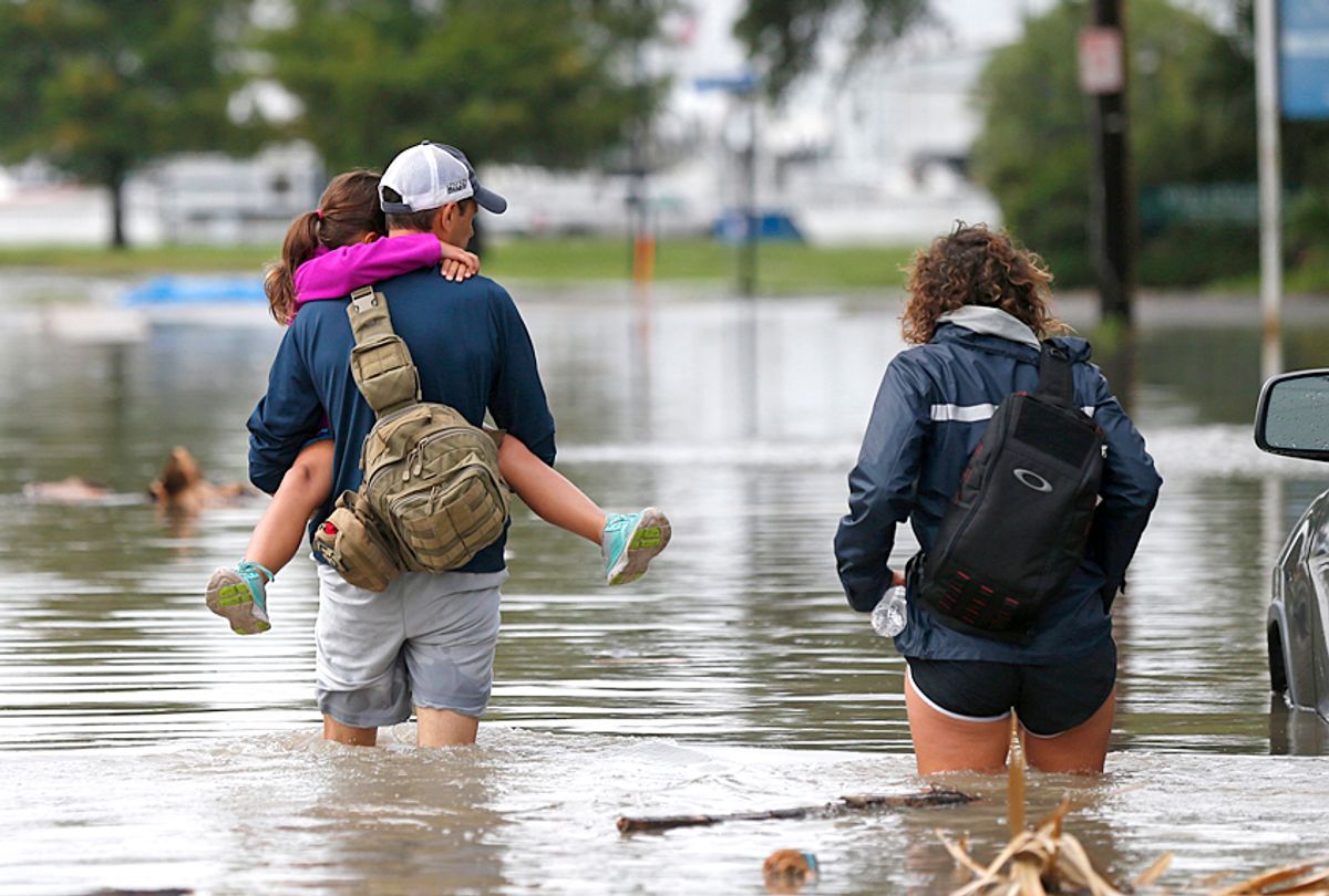 A family walk through a flooded roadway in the West End section of New Orleans (AP/Gerald Herbert)