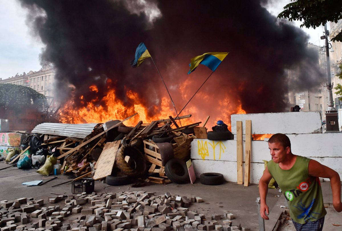A man runs in front of a barricade burned by Maidan self-defence activists as they clash with residents of Kiev on August 9, 2014. (Getty/Sergei Supinsky)